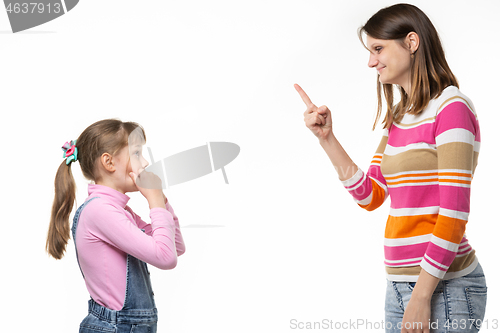 Image of Mom shows the index finger to the girl, daughter looks at mom in fear