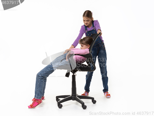 Image of Girl offended by sister sliding off chair on a white background