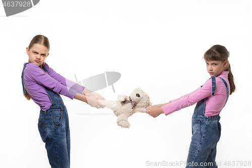 Image of Two disgruntled sisters share a toy on a white background