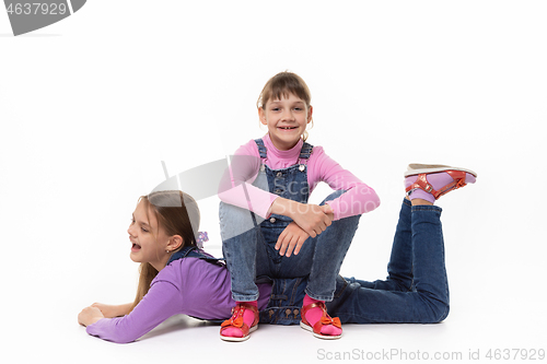 Image of Happy girl sits on her sister\'s back in a white background