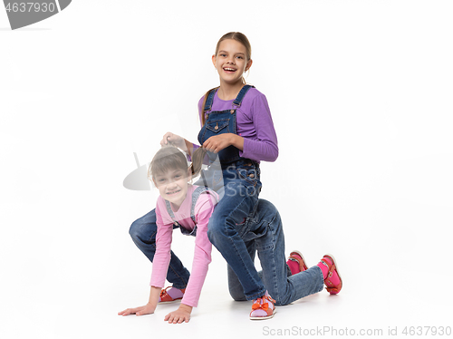 Image of Two sisters play jockey and horse against a white background