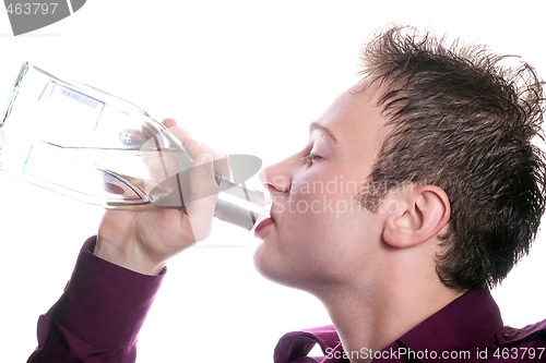 Image of The young man drinks vodka from a bottle