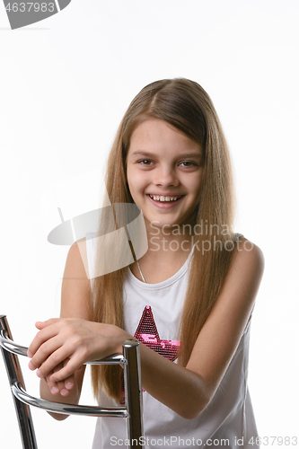 Image of Girl sitting on a high-backed chair and smiling joyfully