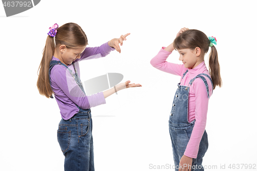Image of A girl shows a virtual object on her hand, another girl looks at her and scratches her head in bewilderment.