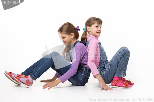 Image of Children sitting on the floor pushing their backs