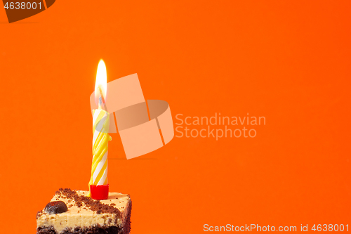 Image of Festive burning candle on a cake on a bright red background