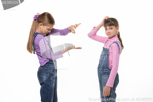 Image of A girl shows a virtual object on her hand, another girl scratches her head in bewilderment