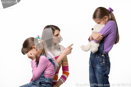 Image of Mom speaks menacingly with a daughter who offended another daughter