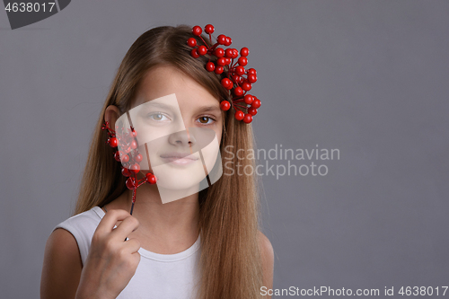 Image of Portrait of a beautiful ten year old girl with a bunch of berries in her hand and hair