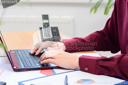 Image of close-up of the hands of an office employee working on a laptop