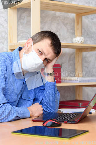 Image of Sad leader sits behind a worker in front of a laptop wearing a protective mask