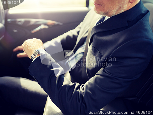 Image of senior businessman driving on car back seat