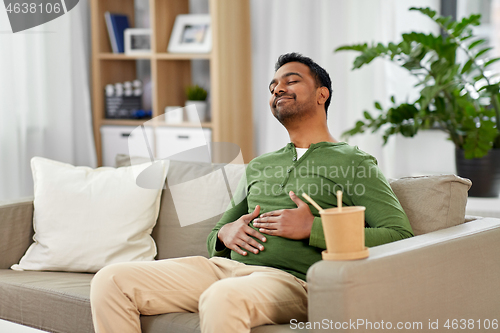 Image of pleased indian man eating takeaway food at home