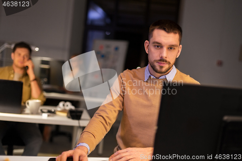 Image of man with computer working late at night office