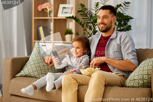 Image of happy father and daughter watching tv at home