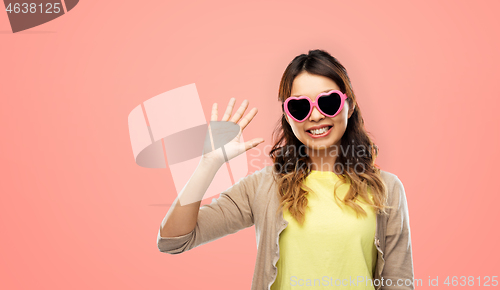 Image of asian woman in heart-shaped sunglasses waving hand