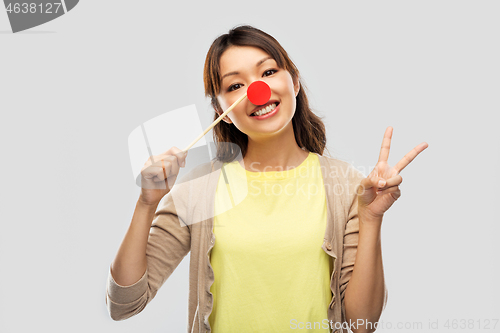 Image of asian woman with red clown nose showing peace