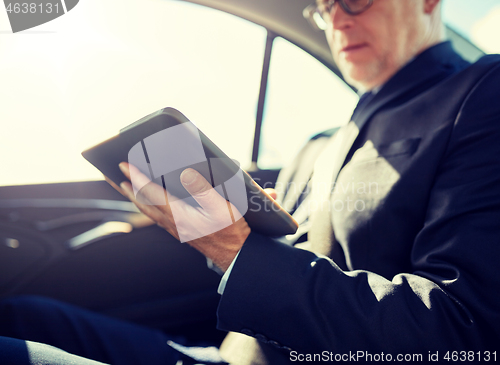 Image of senior businessman with tablet pc driving in car