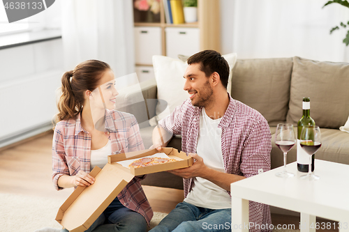 Image of couple with wine eating takeaway pizza at home