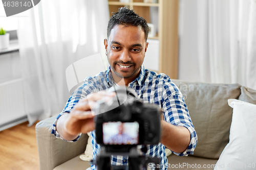 Image of indian male video blogger adjusting camera at home