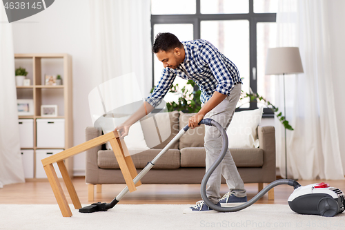 Image of indian man with vacuum cleaner at home