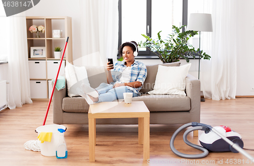 Image of woman in headphones resting after home cleaning