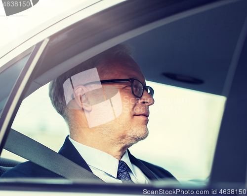 Image of senior businessman driving on car back seat