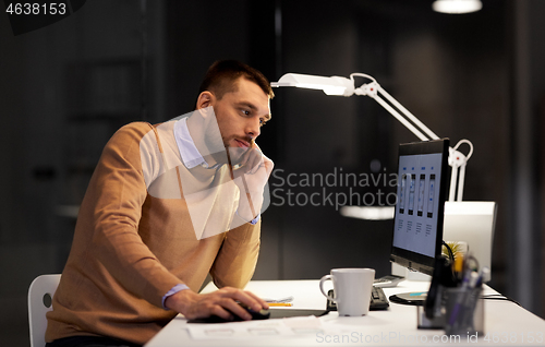 Image of web designer with computer working at night office