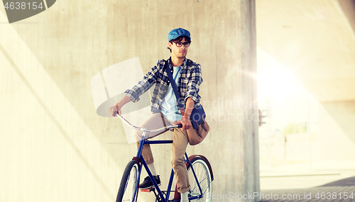 Image of young hipster man with bag riding fixed gear bike