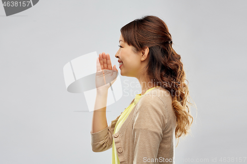 Image of young asian woman calling for someone
