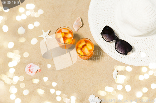 Image of cocktails, sun hat and sunglasses on beach sand