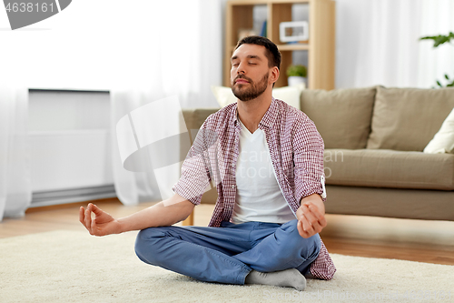 Image of man meditating in lotus pose at home