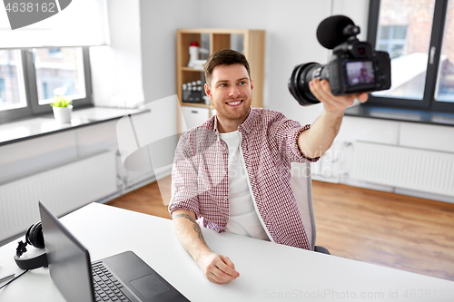 Image of male blogger with camera videoblogging at office