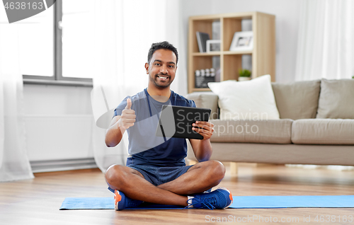 Image of indian man with tablet computer on exercise mat