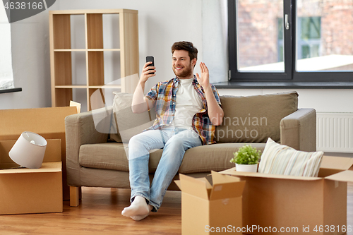 Image of man with smartphone having video call at new home