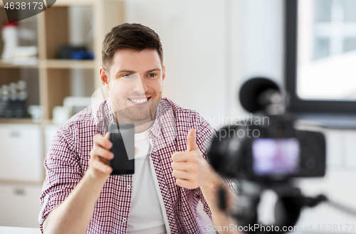 Image of male blogger with smartphone videoblogging at home