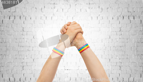 Image of hands with gay pride wristbands in winning gesture