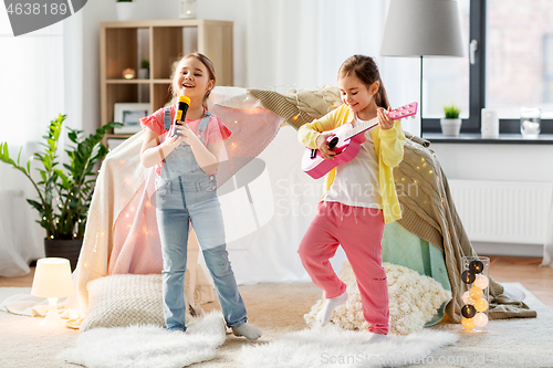 Image of girls with guitar and microphone playing at home