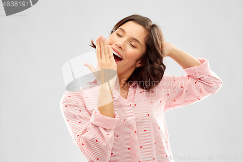 Image of happy young sleepy woman in pajama yawning