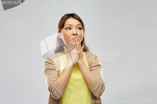 Image of scared asian woman over grey background