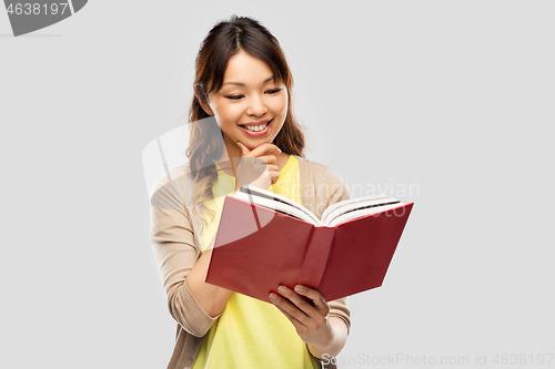 Image of happy asian woman reading book