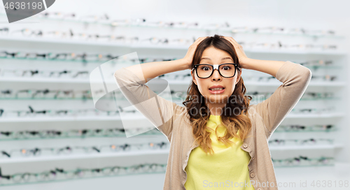 Image of woman in glasses holding to head at optics store