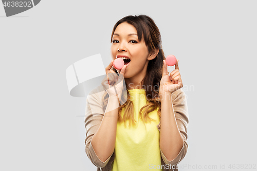 Image of happy asian woman with macarons