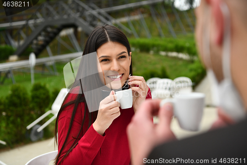 Image of couple with protective medical mask  having coffee break in a re