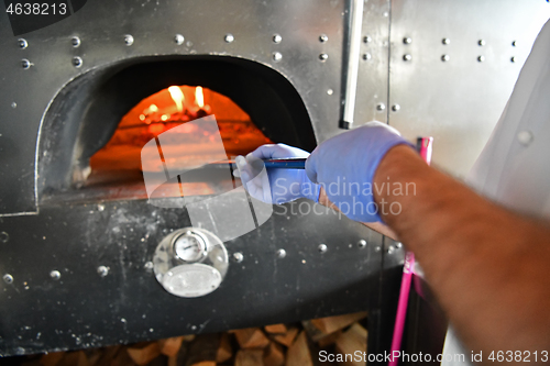 Image of chef  with protective coronavirus face mask preparing pizza