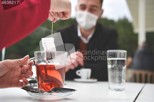 Image of couple with protective medical mask  having coffee break in a re