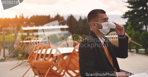 Image of funny man in restaurant drinking coffee wearing face mask