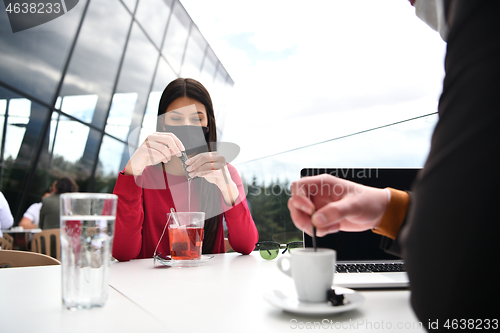 Image of couple with protective medical mask  having coffee break in a re