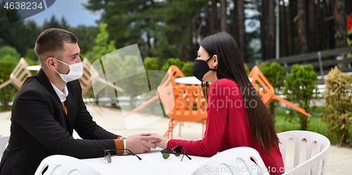 Image of couple with protective medical mask  having coffee break in a re