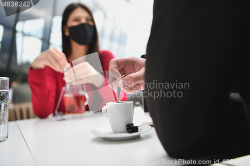 Image of couple with protective medical mask  having coffee break in a re